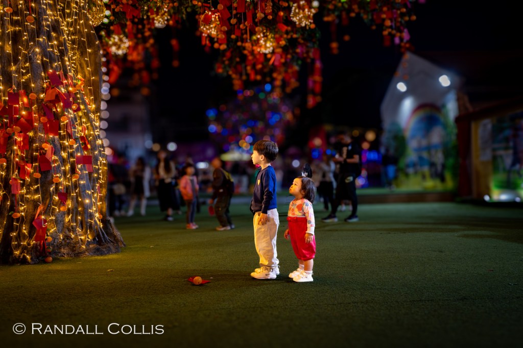 Dusk at the Lam Tsuen Well-wishing festival - two children peering up at the tree